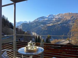 a tea set on a table on a balcony with mountains at Apartment Breithorn-Residence-2 by Interhome in Wengen