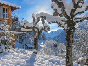 a tree covered in snow next to a house at Apartment Breithorn-Residence-2 by Interhome in Wengen