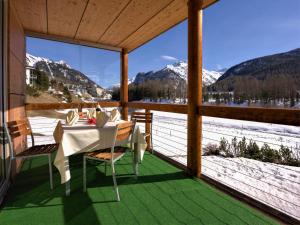 a table and chairs on a porch with a view of mountains at Apartment Chesa Lej by Interhome in Pontresina