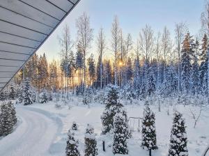 a snowy yard with trees and snow covered trees at Holiday Home Willa klaara by Interhome in Patajoki