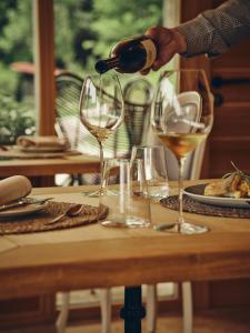 a person pouring wine into two wine glasses on a table at Boutique hotel Vila Planinka in Zgornje Jezersko