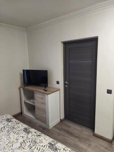 a bedroom with a door and a tv and a bed at Apartment First December in Oradea
