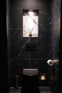 bagno nero con servizi igienici e finestra. di Royal Suite a 's-Gravenzande