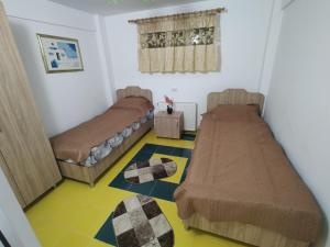 pokój z 2 łóżkami i żółtą podłogą w obiekcie Casa Leny w mieście Călăraşi