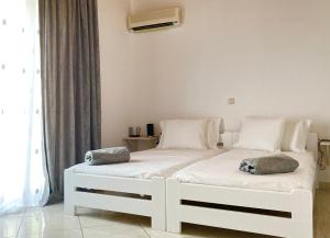 Duas camas brancas num quarto com uma janela em Gerani Maison Agios Aimilianos beautiful view em Porto Heli