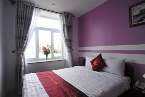 a bedroom with purple walls and a bed with a window at Hong Thien Ruby Hotel in Hue