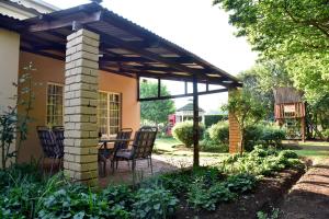 a patio with a table and chairs under a pergola at Villa Moria Peace Cottage in Dullstroom