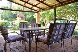 a table and chairs sitting under a pergola at Villa Moria Peace Cottage in Dullstroom