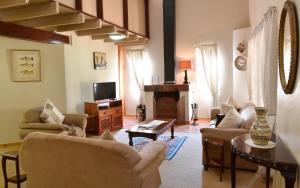 a living room with couches and a tv and a fireplace at Villa Moria Peace Cottage in Dullstroom