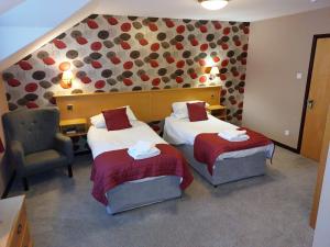 a hotel room with two beds and a chair at County Lodge & Brasserie in Carnforth