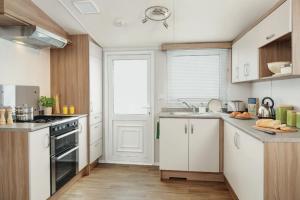 a kitchen with white cabinets and a stove top oven at Heavenly Haven in Lymington