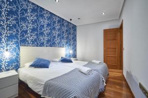 2 camas en un dormitorio con papel pintado azul y blanco en BV Rooms, en Madrid