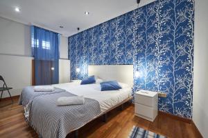 2 camas en una habitación con papel pintado azul en BV Rooms, en Madrid