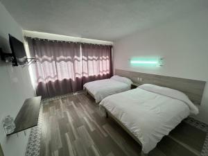 um quarto com duas camas e uma janela em Hotel Insurgentes em San Luis Potosí