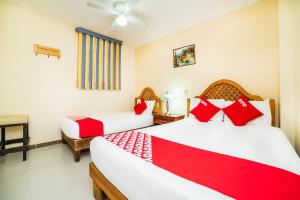 two beds in a room with red and white pillows at OYO Hotel Bugambilia, San Luis Potosí in San Luis Potosí