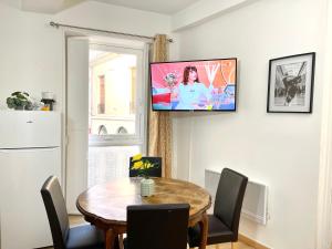 een eetkamer met een tafel en een televisie aan de muur bij Art Apparts coeur de ville in Béziers