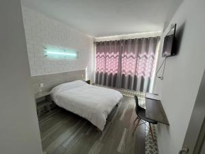 Habitación pequeña con cama, mesa y ventana en Hotel Insurgentes, en San Luis Potosí