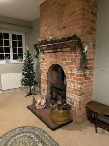 a brick fireplace in a living room with a christmas tree at The Manor Stables in Sturminster Newton