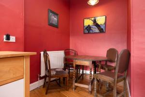 ALTIDO Old Town 1-Bed Apartment with Stunning Views في إدنبرة: غرفة طعام بجدران حمراء وطاولة وكراسي