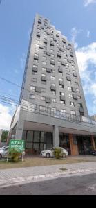 un gran edificio con coches estacionados frente a él en Ilusion flat Ponta Negra, en Natal