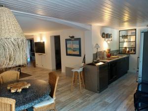 a living room with a table and a kitchen at Pomme de Pin et Mimosa in Grand-Village-Plage