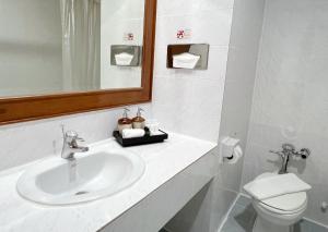 a bathroom with a sink and a toilet and a mirror at The Promenade Hotel - SHA Plus in Bangkok