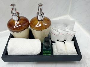 a tray with two bottles and towels and toiletries at The Promenade Hotel - SHA Plus in Bangkok