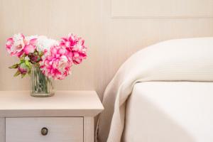 a vase of pink flowers sitting on a table next to a bed at Hotel Dei Pini in Alghero