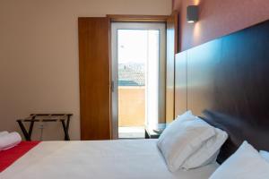 a bedroom with a bed with a large window at Flag Hotel Barcelos in Barcelos