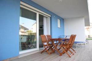 une table et des chaises en bois assises sur une terrasse dans l'établissement RESIDENCE BLUMAR, à Lido di Jesolo