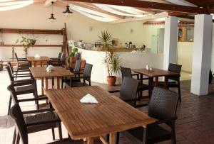 un restaurant avec des tables et des chaises en bois et un comptoir dans l'établissement Corfu Pearl, à Liapades