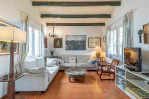 a living room with a couch and a tv at Villa Araucaria in Cala en Bosc