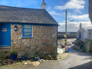 an old stone house with a blue door at Sweet Caroline - luxury studio stone’s throw from Mousehole harbour in Mousehole