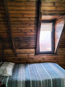 Ce lit se trouve dans une cabane en rondins dotée d'une fenêtre. dans l'établissement Zifinbungalov, à Akcaabat