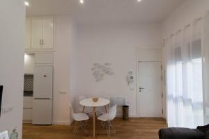 een witte keuken met een tafel en witte stoelen bij Apartamento Las 3 Gaviotas in Cádiz