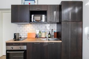 a kitchen with brown cabinets and a sink and a microwave at The Beach apartments by Daniel&Jacob's in Copenhagen +69 photos