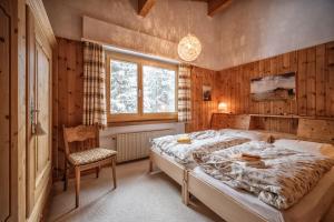 a bedroom with a large bed and a chair at Casa Dschember, Wohnung 10, 1-5 Personen in Arosa