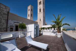 a balcony with white chairs and two towers at MoMa Molfetta Mare in Molfetta