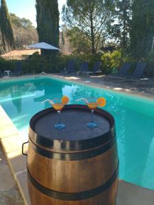 Una piscina con un barril de madera con dos copas de martini. en la villa des six ifs - Le mûrier, en Flayosc