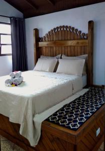 a bedroom with a large wooden bed with towels on it at Pousada Casa do Oscar in Governador Celso Ramos
