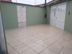 an empty room with a garage with a white tiled floor at Linda casa novinha in Mongaguá