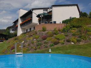 a large blue swimming pool in front of a house at Pension Haus Wanninger in Warmensteinach