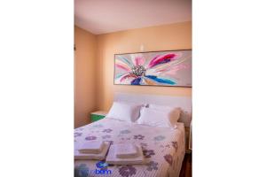 a bedroom with a bed with a flower painting on the wall at Colors 4 pessoas | wi-fi | garagem | ladinho da Praça das Flores in Nova Petrópolis