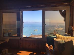 a person sitting on a couch looking out a window at the ocean at Villa Kon Tiki with private beach in Dahab