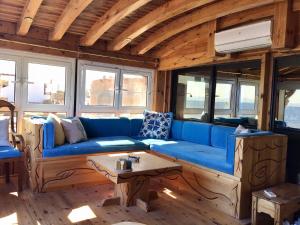 Villa Kon Tiki with private beach في دهب: غرفة معيشة مع أريكة زرقاء وطاولة
