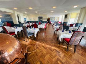 uma sala de jantar com mesas brancas e cadeiras vermelhas em Langham Hotel Eastbourne em Eastbourne