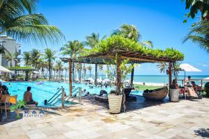 einen Pool mit einem Resort mit Palmen und dem Meer in der Unterkunft Cumbuco Wai Wai Apartamento com vista para o mar in Cumbuco