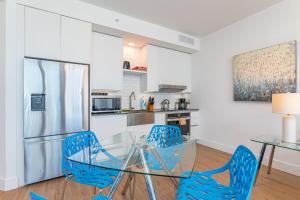 Global Luxury Suites Miami Worldcenter في ميامي: مطبخ مع طاولة زجاجية وكراسي زرقاء