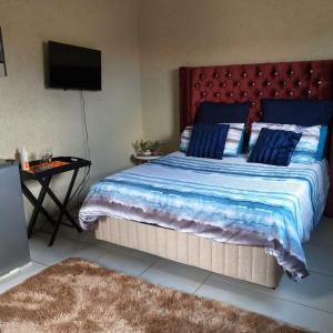 - une chambre avec un grand lit et une table avec une télévision dans l'établissement Lapa la Bakgatlha, à Soweto