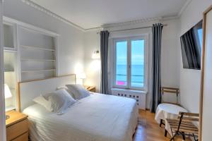 ein Schlafzimmer mit einem großen weißen Bett und einem Fenster in der Unterkunft Gîte de la Plage in Étretat